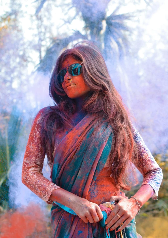 a woman dressed in traditional indian dress with colorful powder on her face and eyes