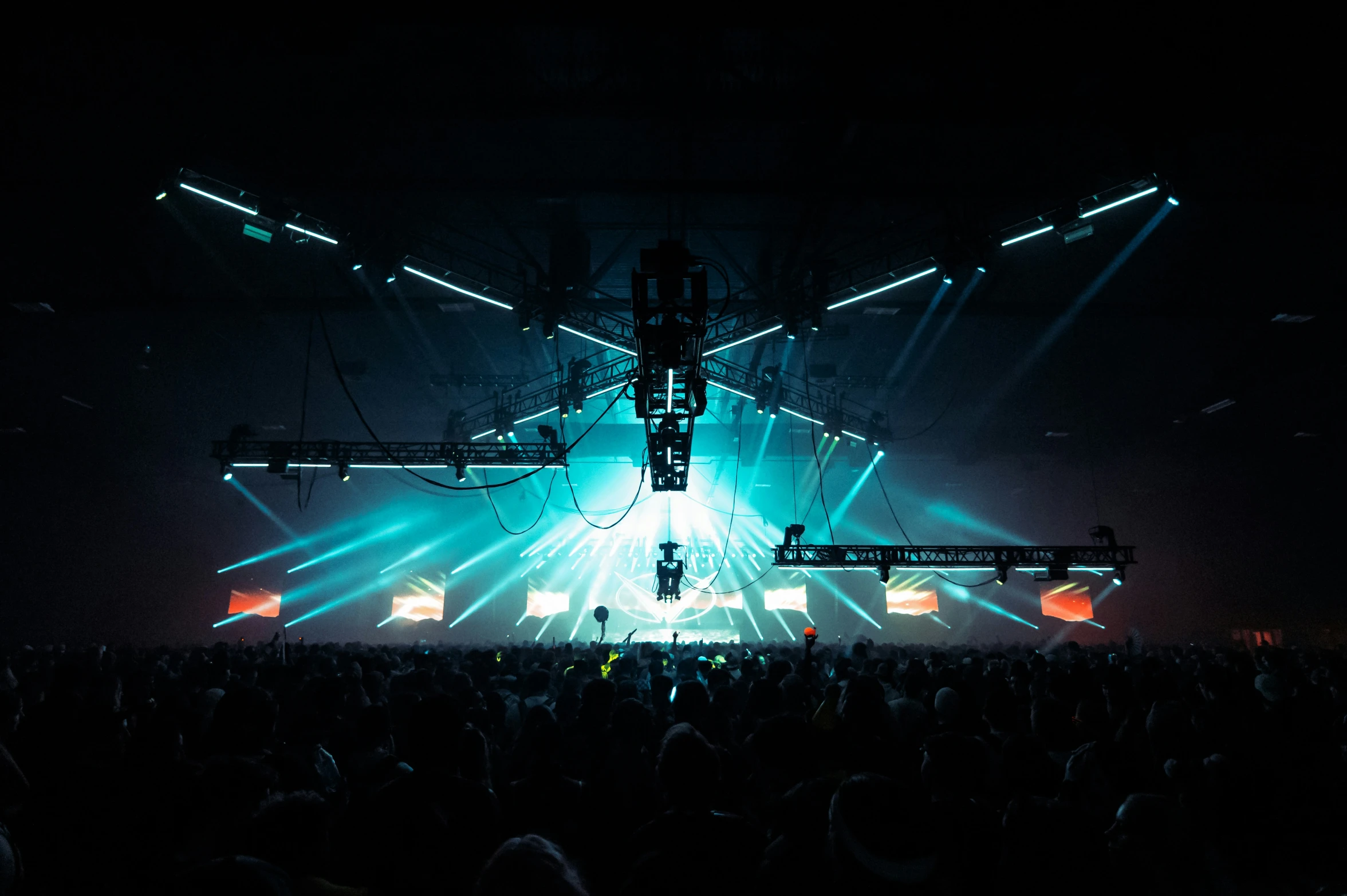 a crowd watches an illuminated stage set during a concert