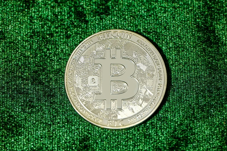 a bit coin laying on top of a green surface