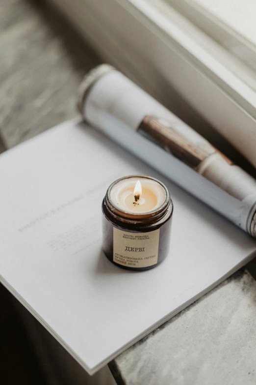 a candle sitting next to a window with a pen