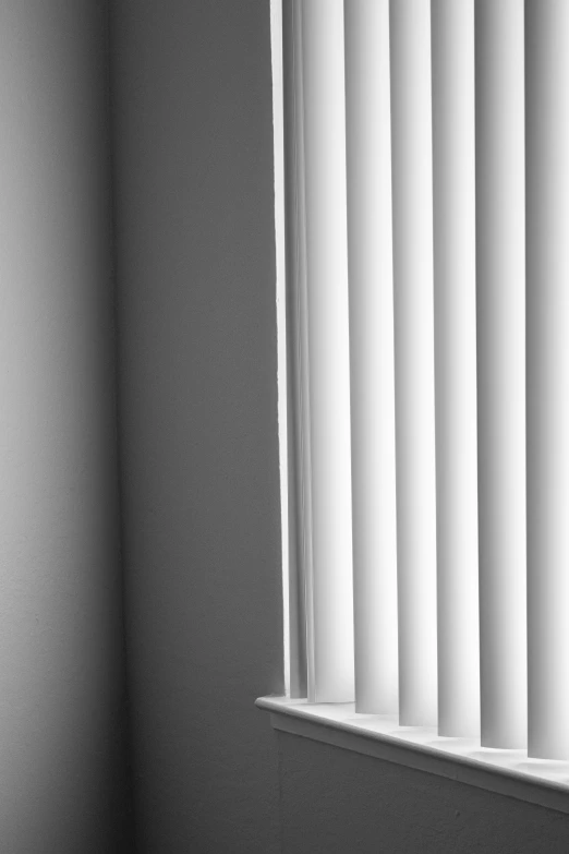 a bathroom with white walls and two windows covered in blinds