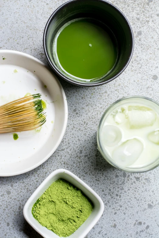 a table has two bowls of matcha and a cup of milk