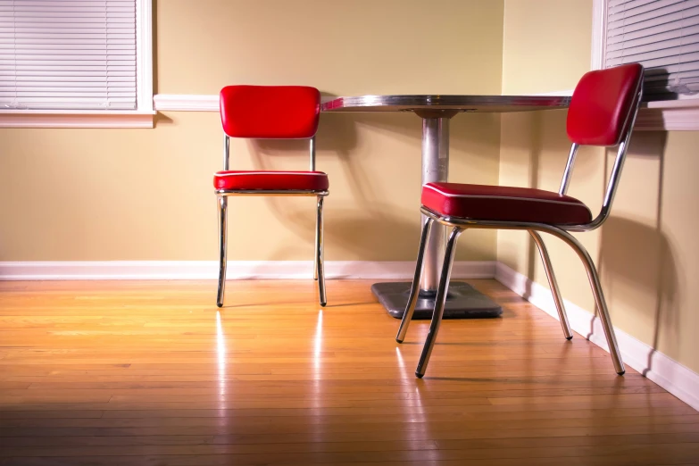 a table and two chairs with blinds on a wall in a room