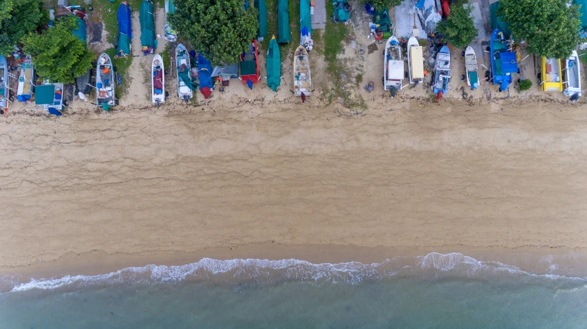 an aerial view of an empty beach with colorful surfboards and a blue boat