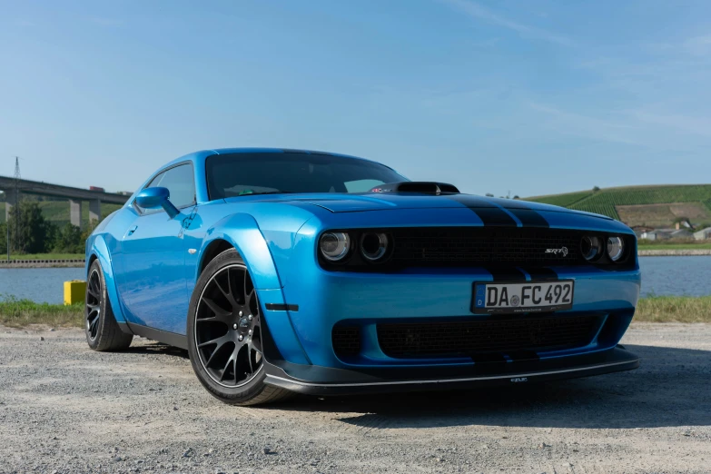 a blue muscle car is parked next to some water