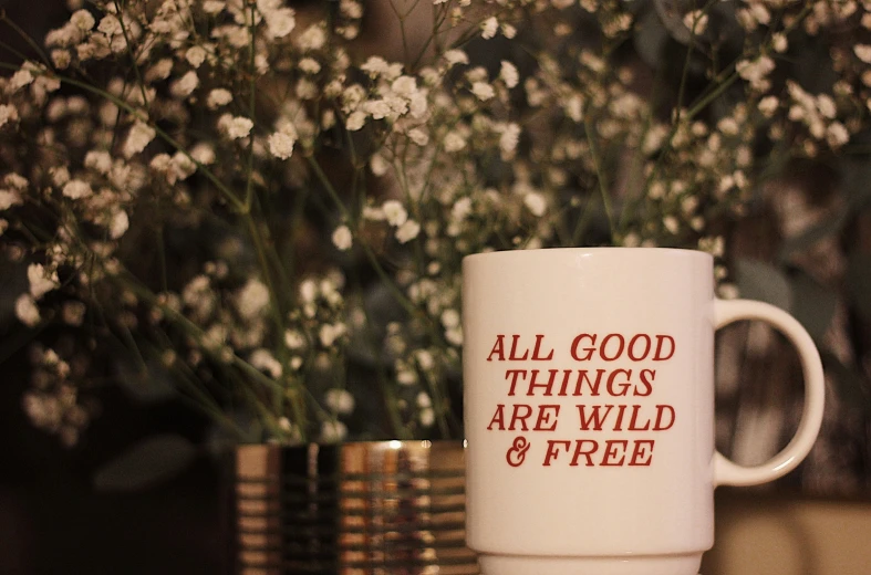 a mug with a poem on it is sitting next to some flowers