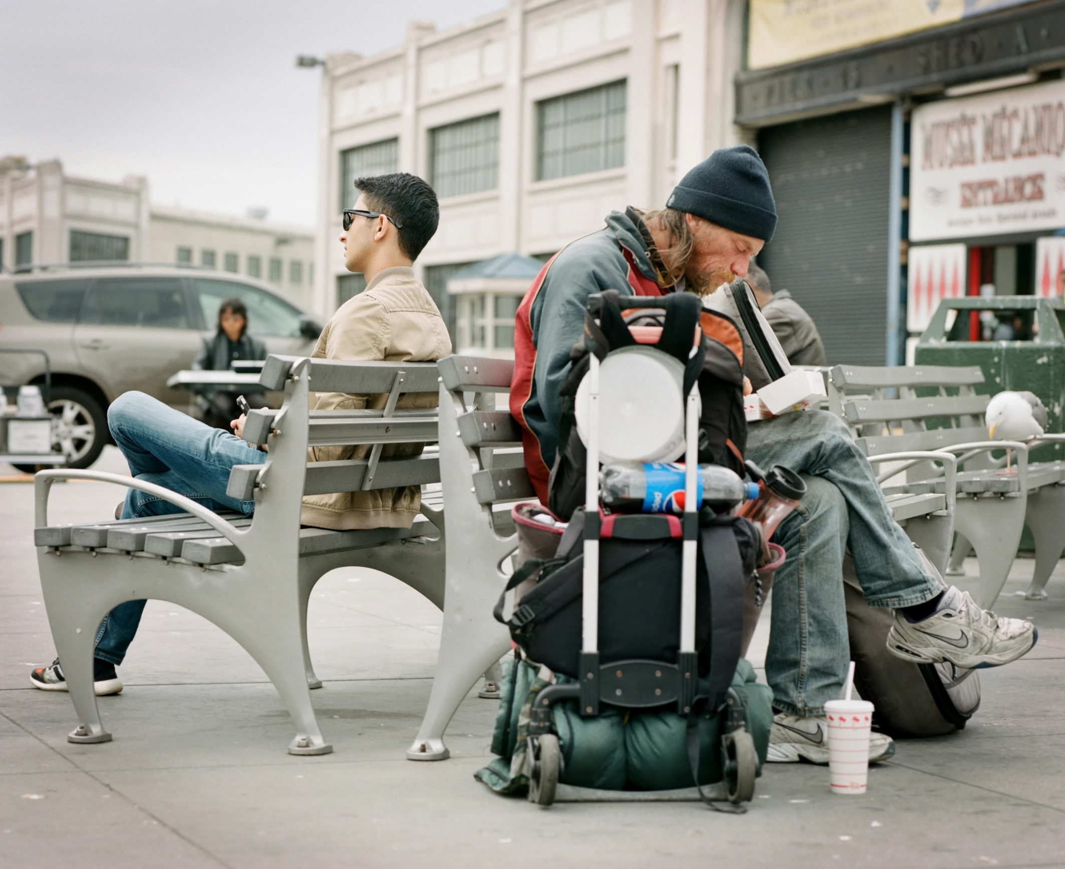 two men sitting on benches and eating food