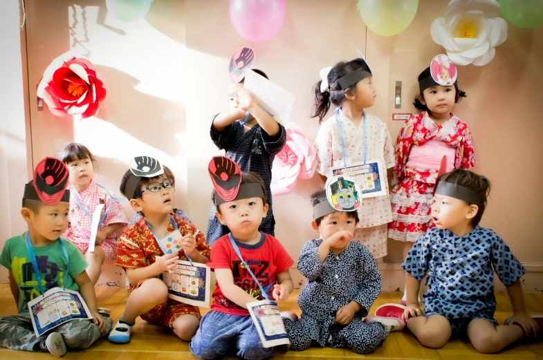 many children sit on the ground while one child holds a cake