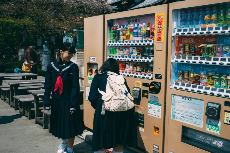 two people look at vending machines on the side walk