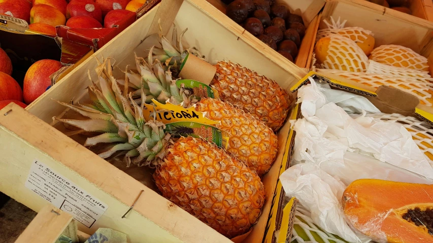 fruit, and a package of pineapples on display in wooden crates