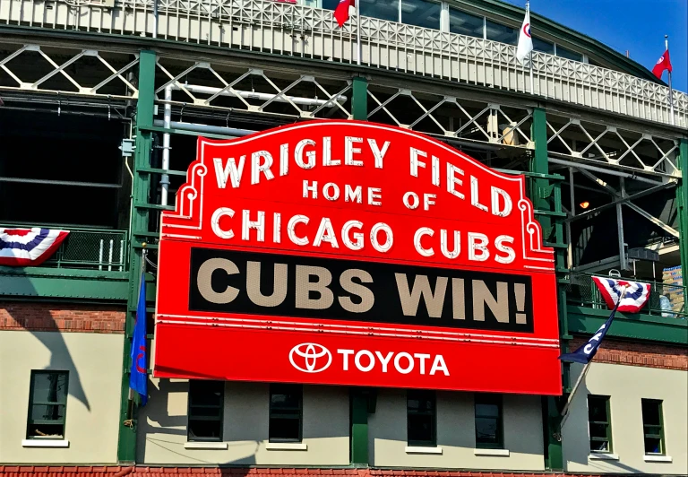 there is a large red sign that is in front of a baseball stadium