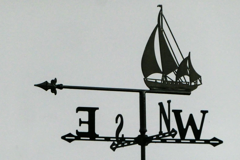 a wind vane on a metal pole with a boat on it