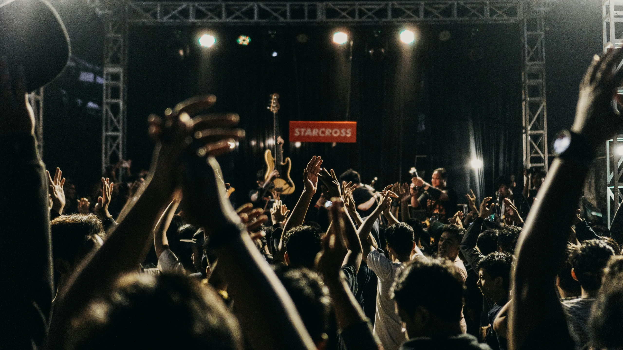 a crowd is clapping and holding up their hands