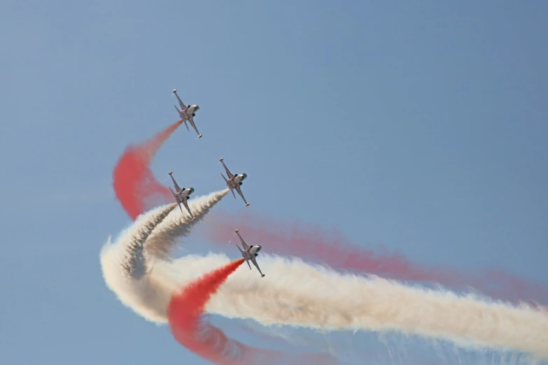 four airplanes flying in the sky leaving contrails