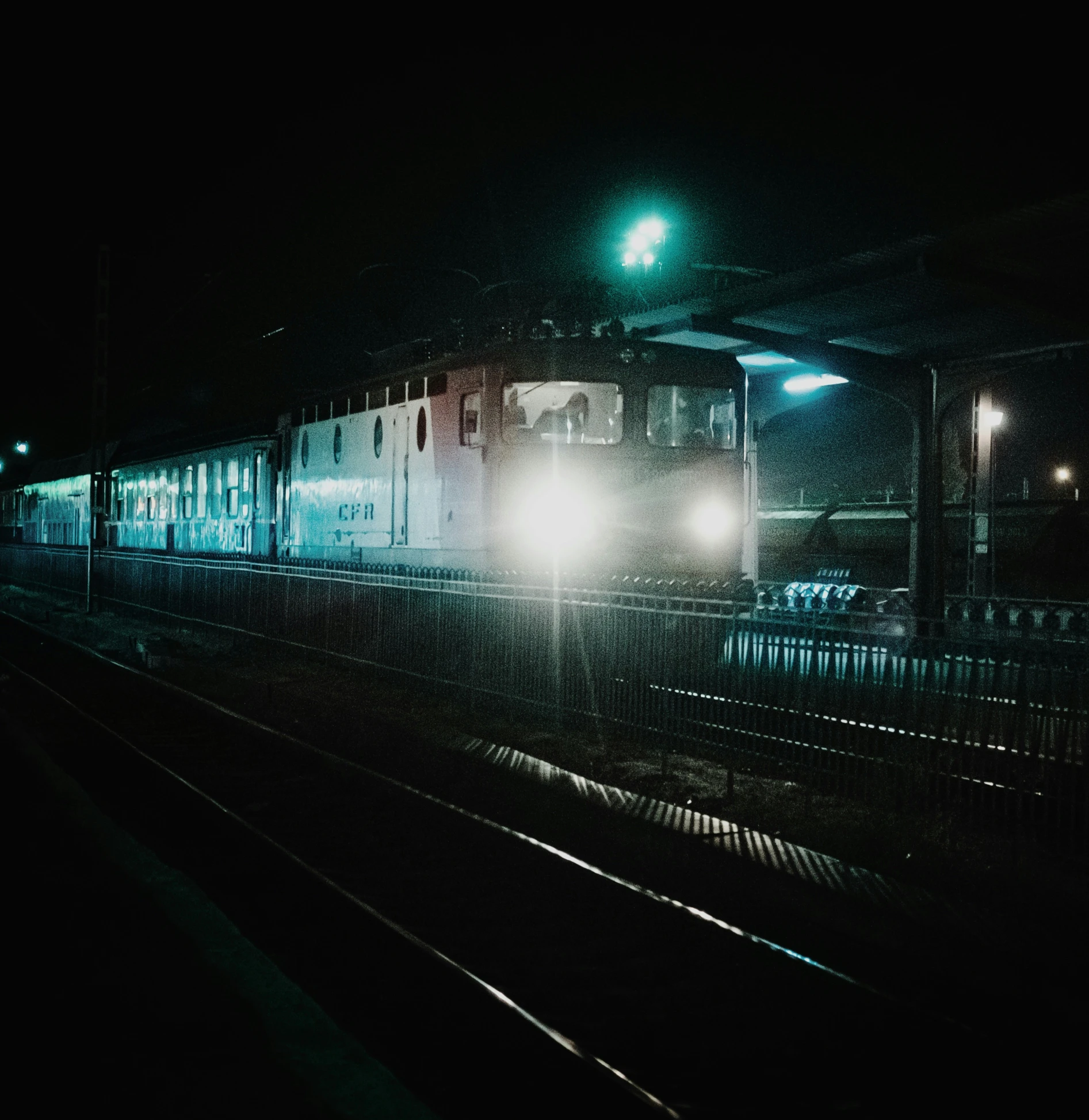 a train traveling at night with the headlights on