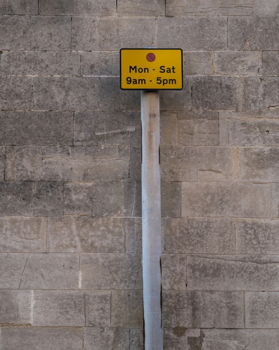 a yellow street sign that is next to a brick wall