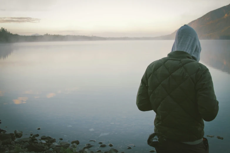 man standing on the edge of a body of water looking out