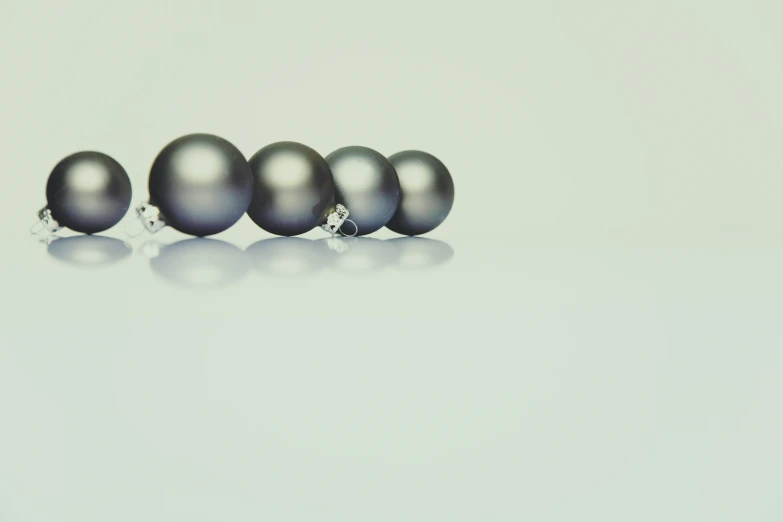 a bunch of shiny black pearls in row on light gray background