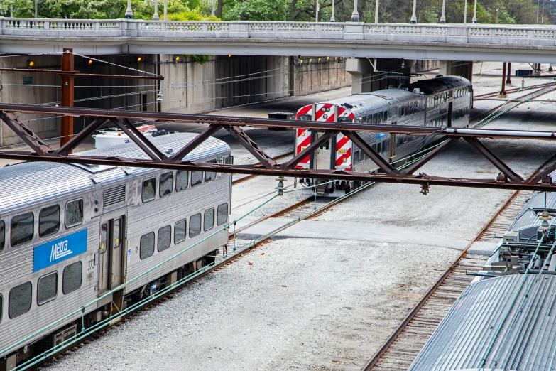 two trains are traveling down the tracks under a bridge