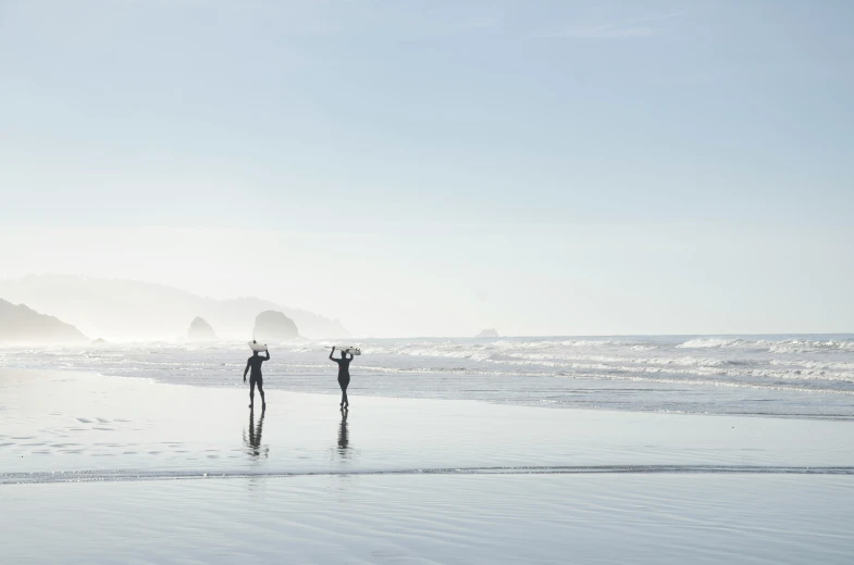 two surfers standing on the shore of the ocean