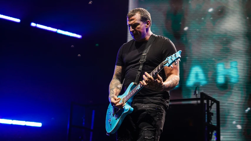 the musician playing a guitar on stage at a concert