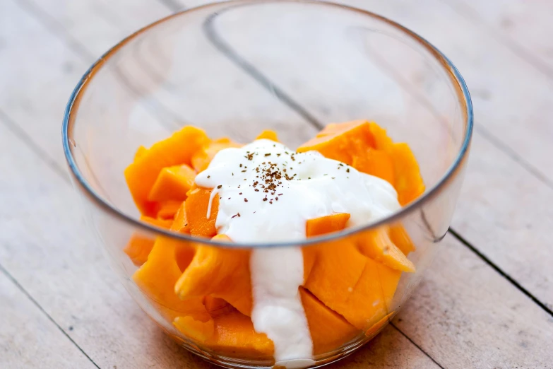 a glass bowl of carrots, bananas and whip cream