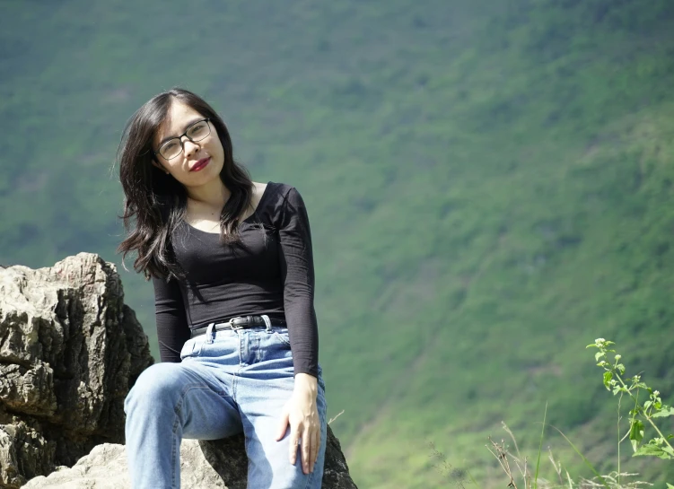 a woman is sitting on a large rock