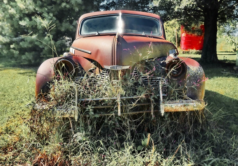 an old rusted out truck in the grass