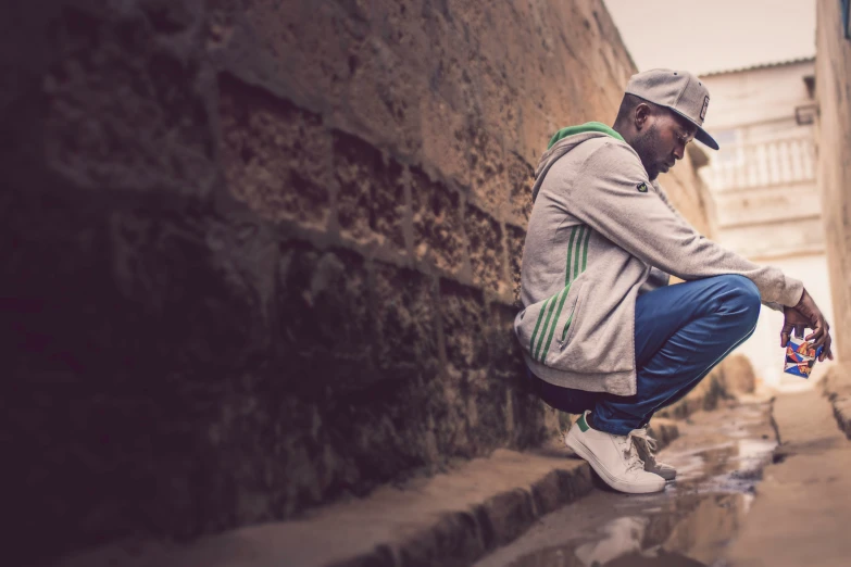 a man squatting on some steps with his hands in his pockets