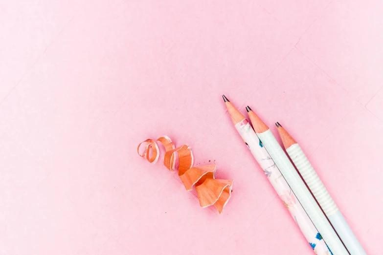 two pencils and a pair of orange heart shapes next to a sharpener