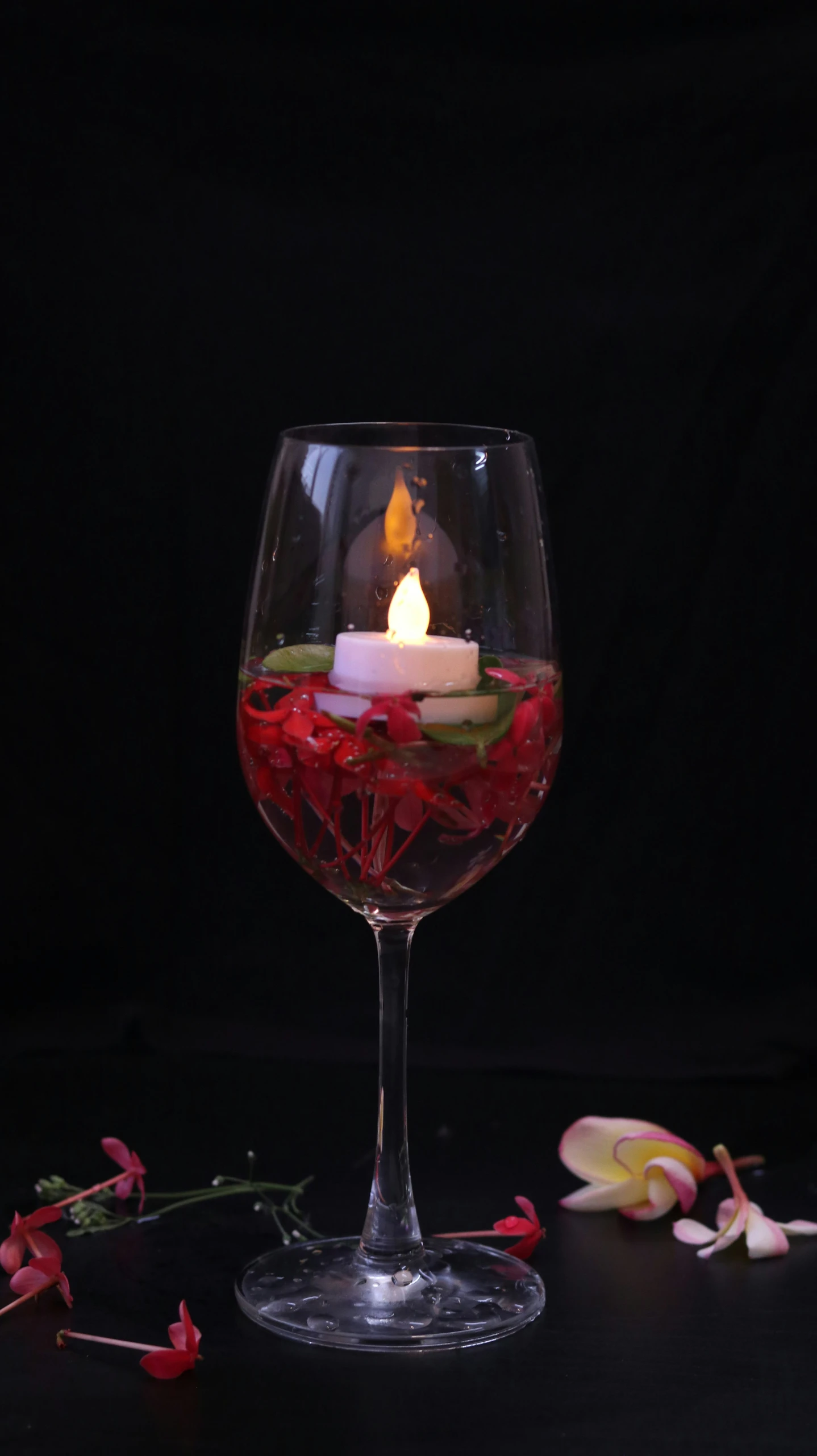 a candle with a glass of red wine on the table