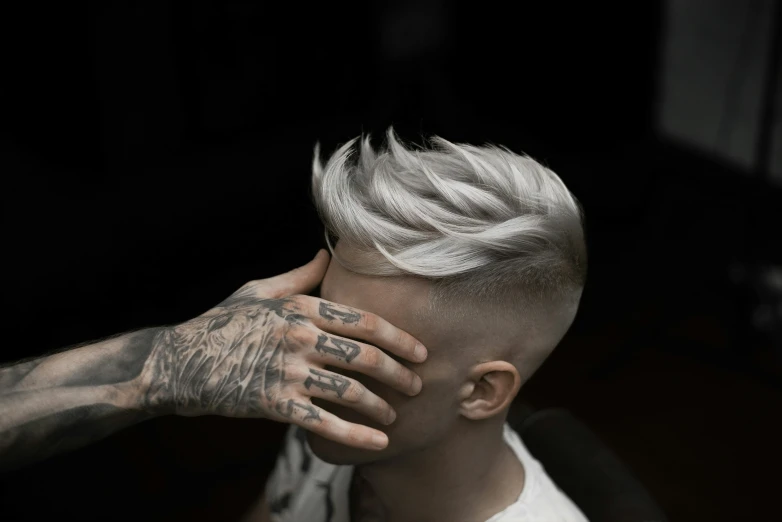 a man with short hair and tattoos puts his hands on his head