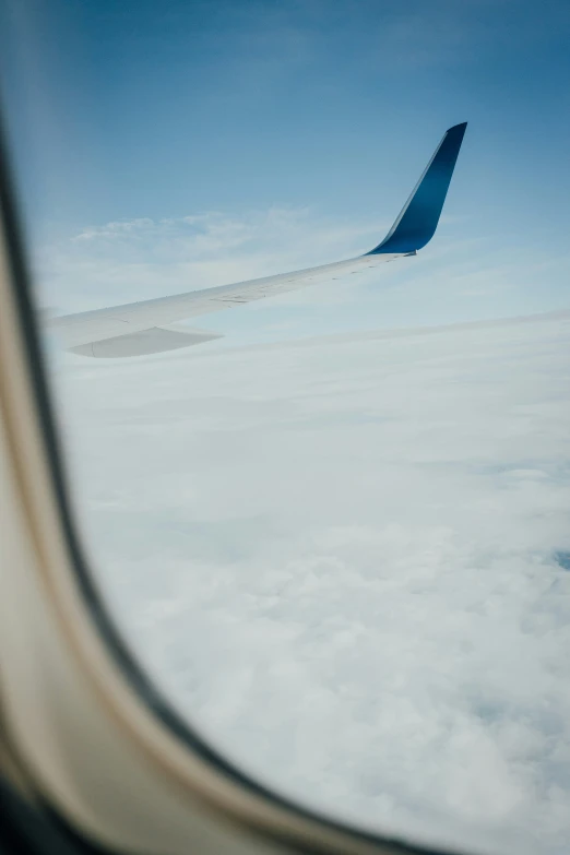 an airplane wing flying over a cloud covered sky