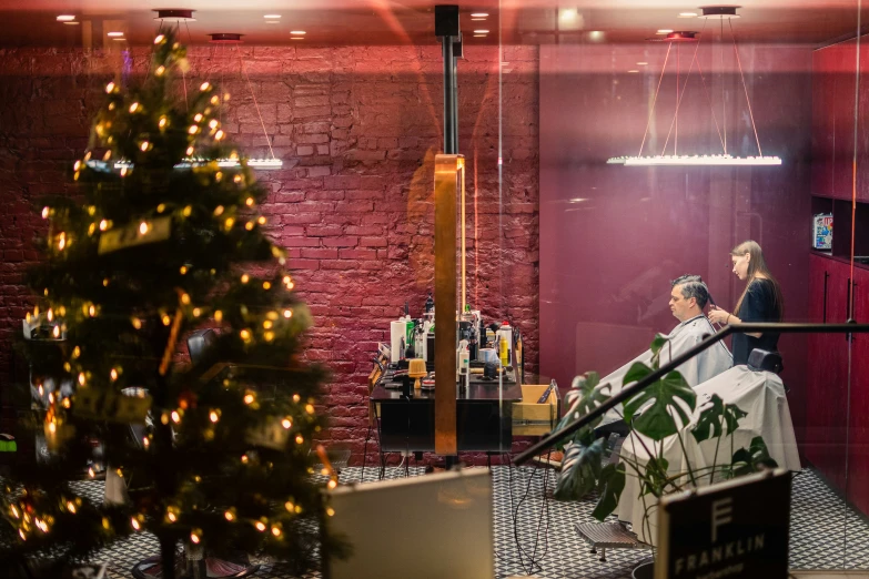 a woman getting her hair styled in front of a christmas tree