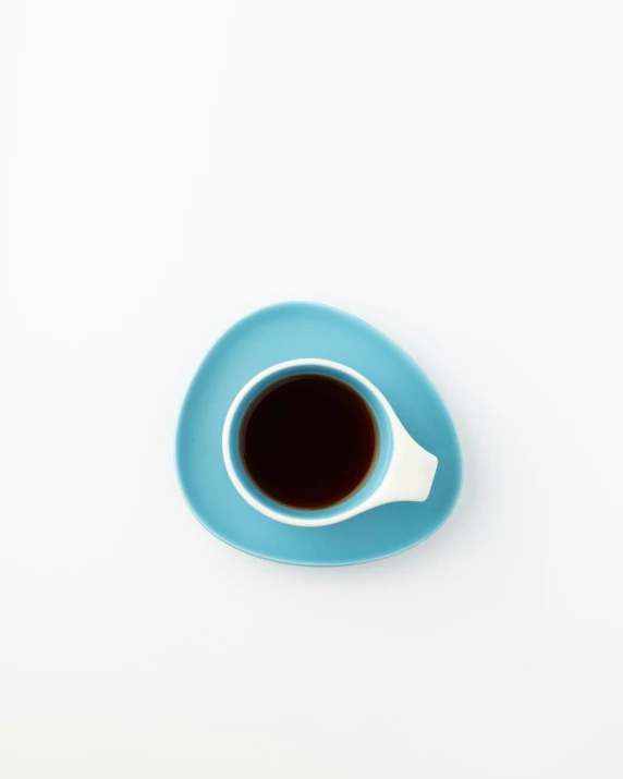 a blue saucer filled with brown liquid on a white table