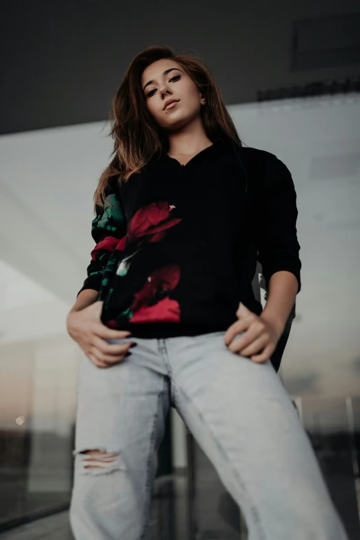 a woman poses while wearing jeans and a sweatshirt