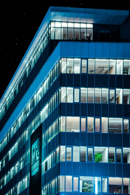 a blue building at night with multiple windows