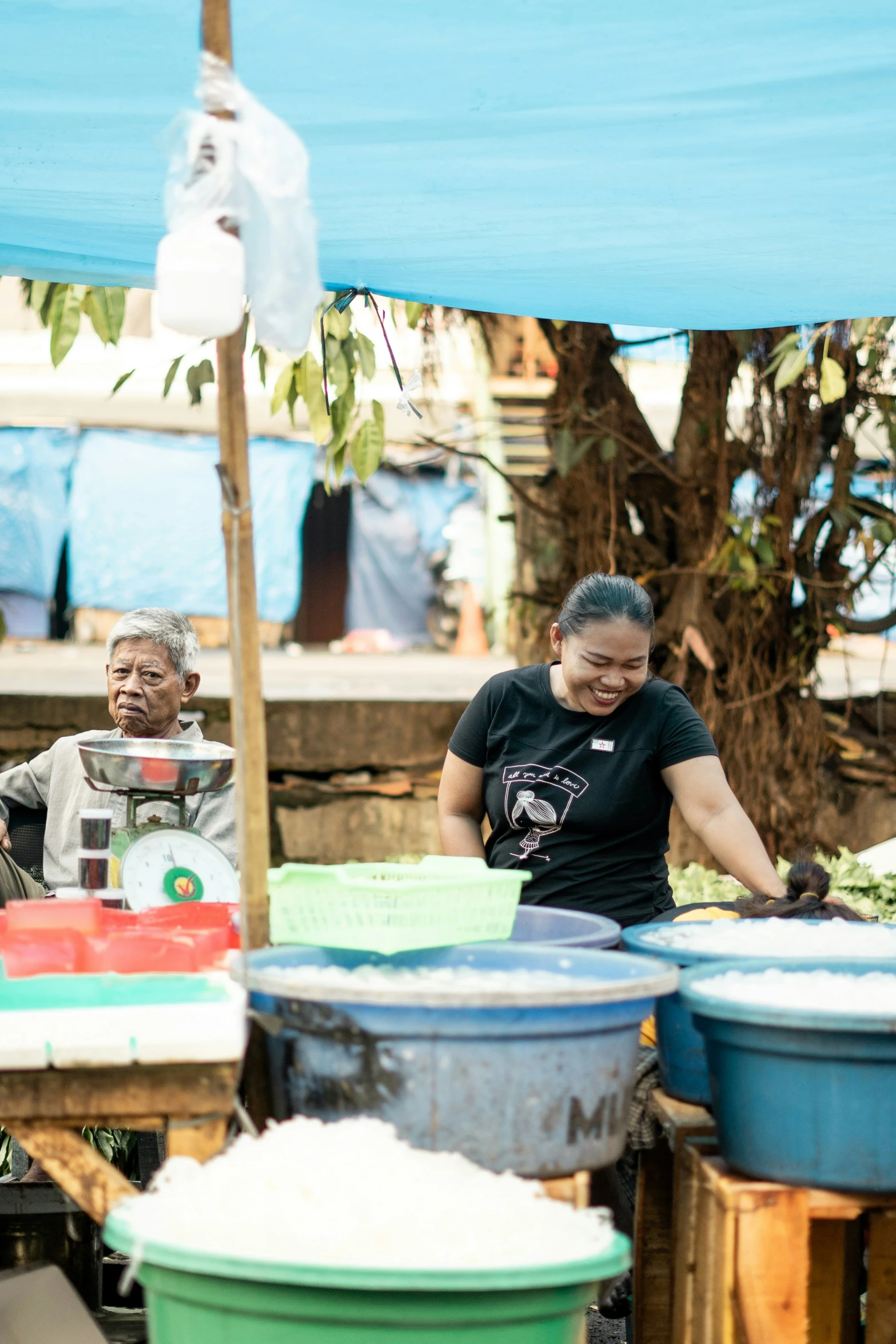 woman and man stand around with a large bucket and a blender