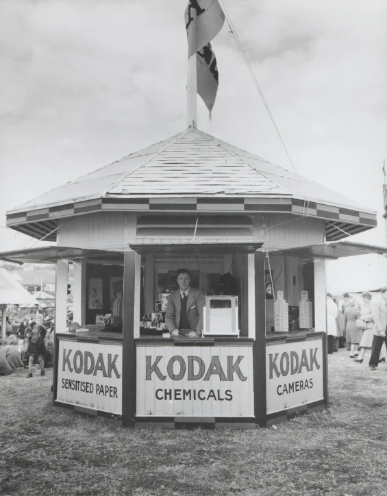 a man is selling kodak chemicals from a kiosk