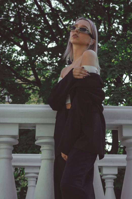 a young woman wearing glasses standing in front of a railing