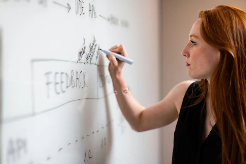 a woman writes on the board with a marker