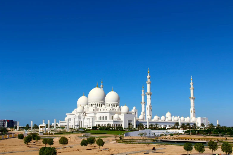 a white building with a lot of trees and a blue sky