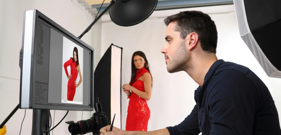 man holding camera standing in front of tv screen