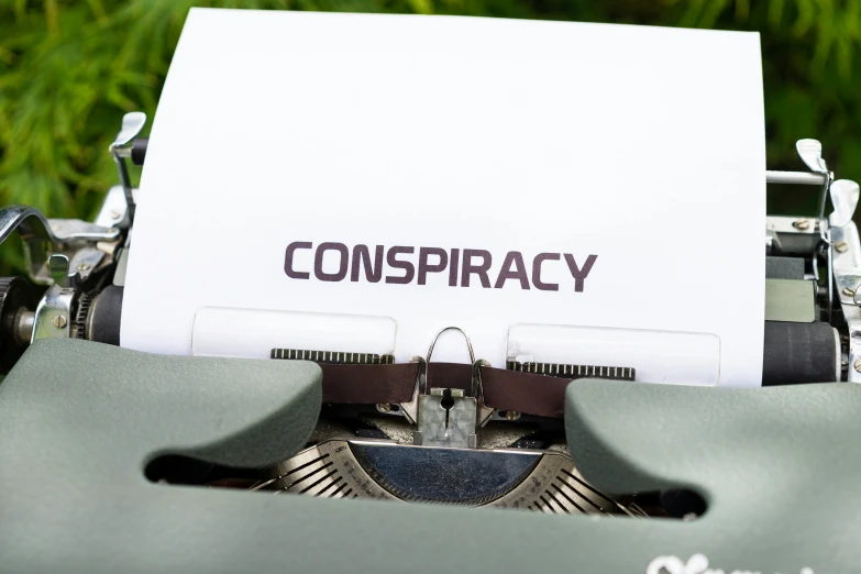 a typewriter that has a paper with the word conspiracy on it