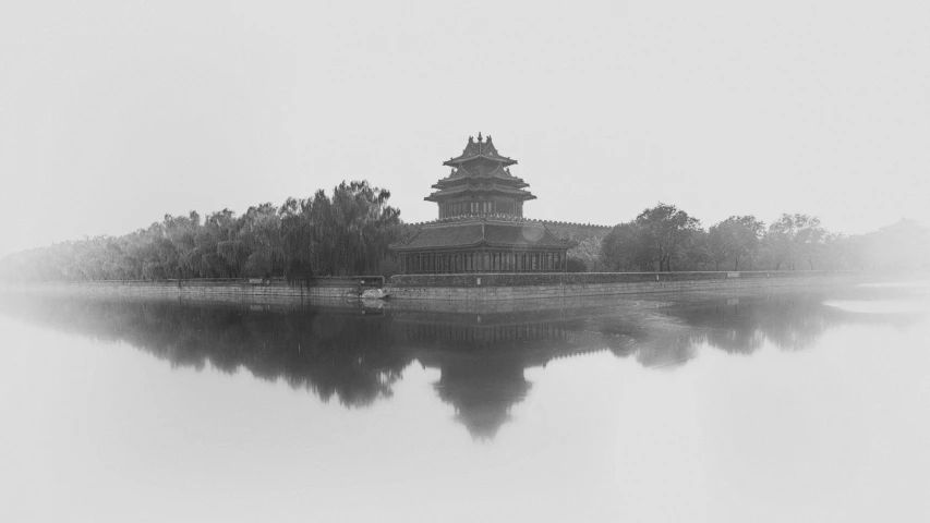 the fog hangs over the water by the temple