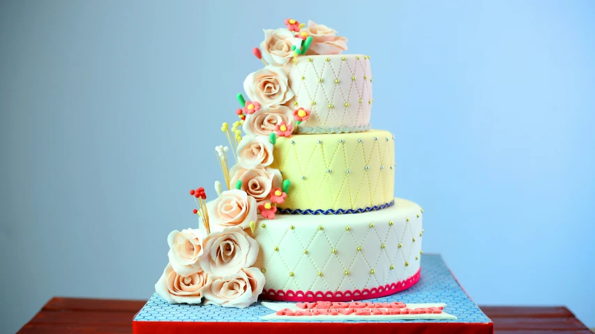 a three layer cake with flowers and writing utensils