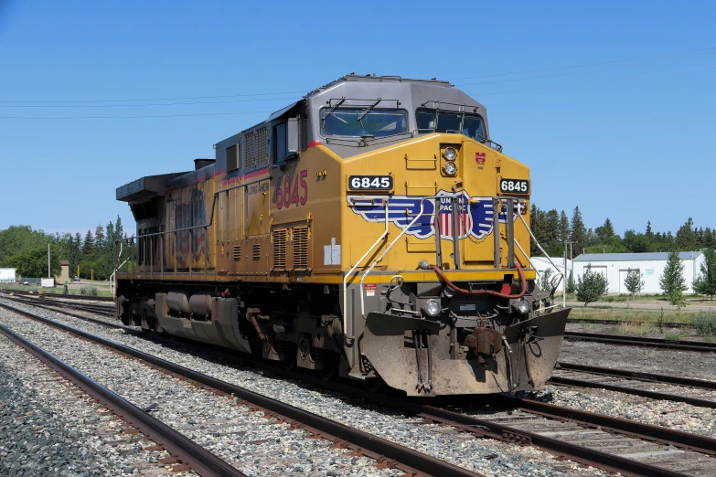 a yellow train sits on the tracks beside the fence