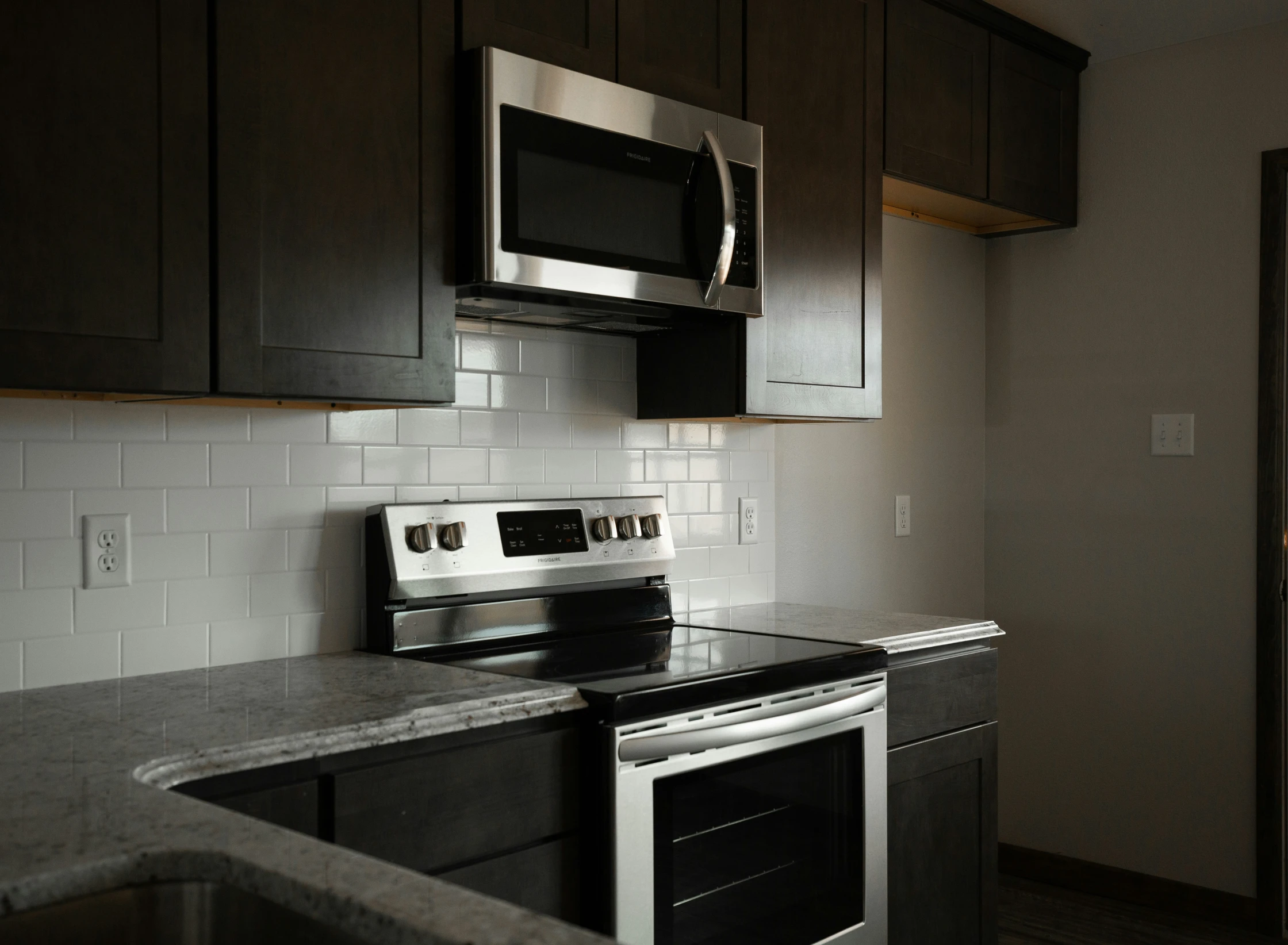 a kitchen with a stove, microwave, and sink