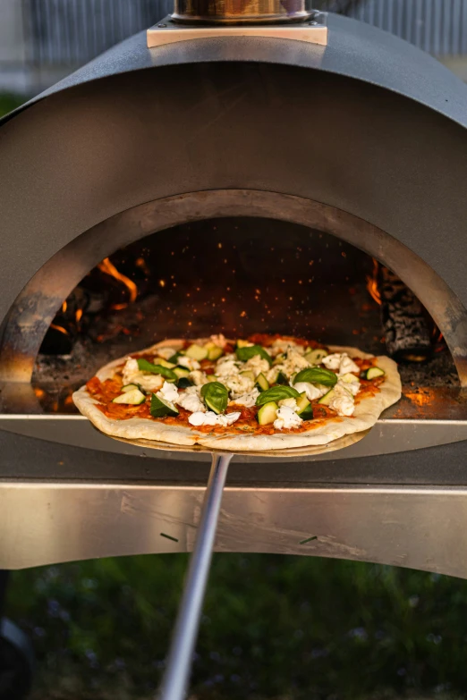 a small pizza is being cooked inside of an outdoor oven