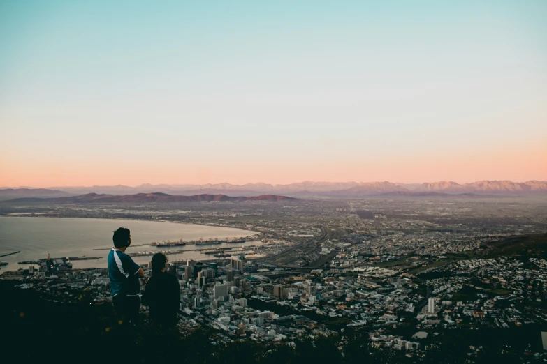 two people looking over a city skyline at sunset